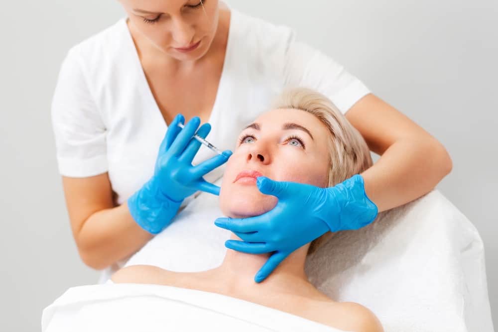 woman getting cheek filler from a professional